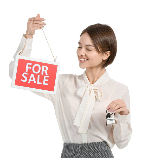 Agente inmobiliario femenino con letrero "Venta" y llave sobre fondo blanco - Foto, Imagen