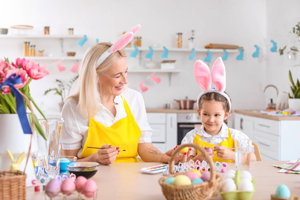 Niña y su abuela pintando huevos de Pascua en casa - Foto, imagen