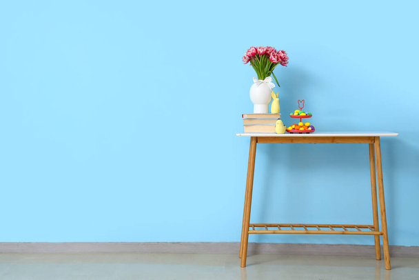 Mavi duvarın yanında vazo, lale, kitap, dekor ve paskalya yumurtaları. - Fotoğraf, Görsel