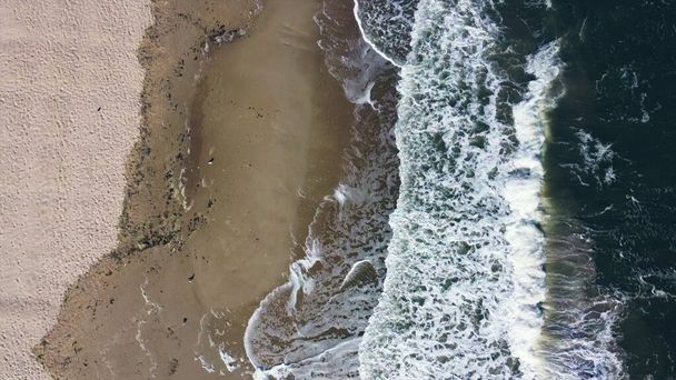 Aerial drone view flight over sea waves that roll onto sandy shore. - Photo, Image