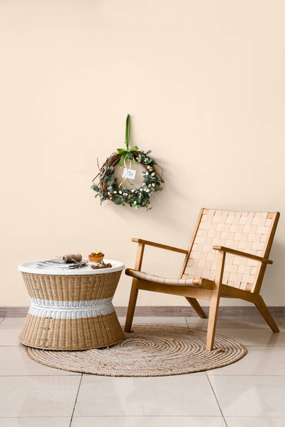 Chaise confortable, table et décoration de Pâques près du mur de couleur à l'intérieur de la chambre - Photo, image
