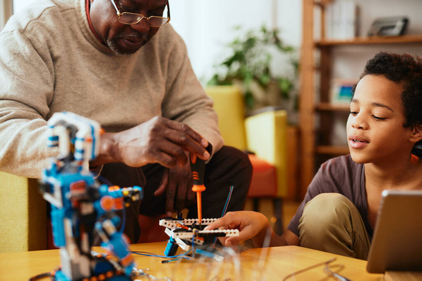 A grandad and grandson making a robot together at home. Education in robotics and electronics. - Photo, Image