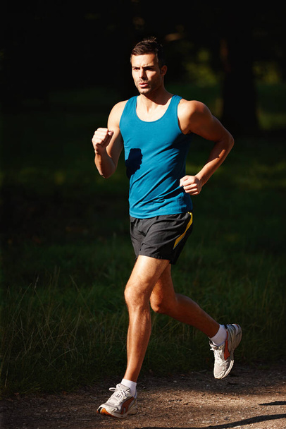 Not even a drop of sweat. Shot of a handsome young man taking a jog outdoors. - Photo, Image