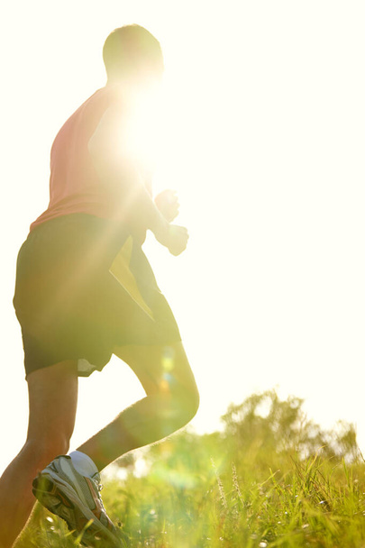 Біжить на сонячному світлі. Знімок заднього виду молодого чоловіка, що біжить на відкритому повітрі на гірській стежці
. - Фото, зображення