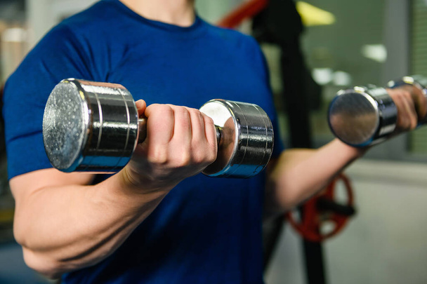 Male muscular hands hold metal dumbbells weights in gym indoors, sportive lifestyle, cropped body with no face - Fotografie, Obrázek