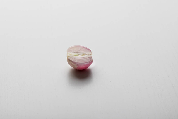 Red onion halves lie on a white table. - Fotó, kép