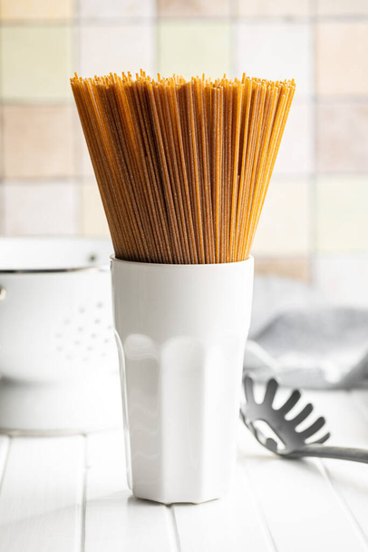 Uncooked whole grain spaghetti. Raw pasta in a cup. - Photo, image