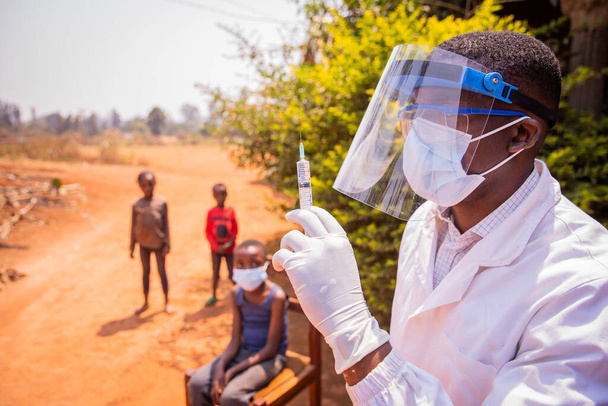 Afrykański lekarz zamierza zaszczepić dzieci, aby zapobiec zakażeniu koronawirusem. Koncepcja szczepień w Afryce - Zdjęcie, obraz