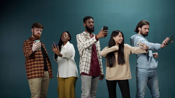 Un grupo multirracial de mejores amigos está sonriendo y tomando fotos en sus teléfonos - Foto, imagen