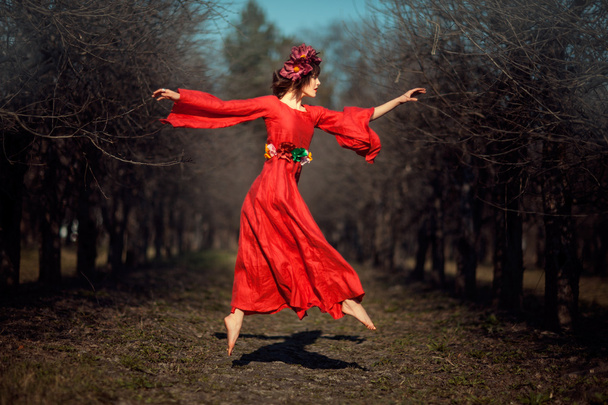 κορίτσι με κόκκινο φόρεμα που πετά στα ύψη. - Φωτογραφία, εικόνα