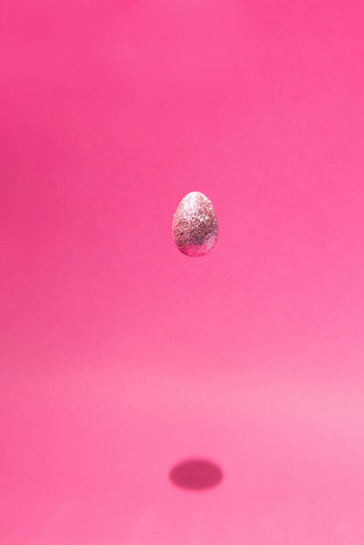 ピンクの背景に光沢のある卵と創造的な楽しいイースター組成。最小限の休日の概念. - 写真・画像