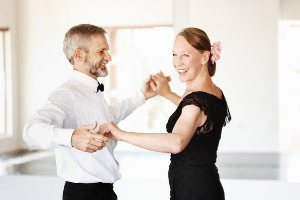 Nog jong van hart. Shot van een volwassen paar dansen samen in formele kleding. - Foto, afbeelding