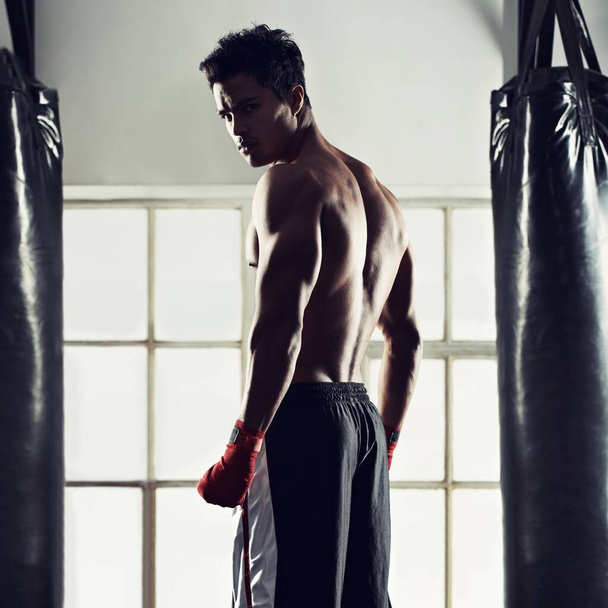 Zajmuje się sportem bokserskim. Portret przystojnego młodego boksera stojącego na siłowni. - Zdjęcie, obraz
