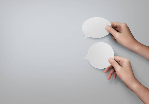 Two hands holding empty speech bubble and cloud bubble on gray background. - Fotó, kép
