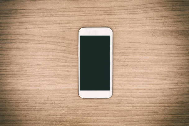 Smart phone on wooden background - vintage style. - Photo, Image