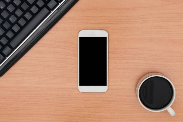 Top view of wooden desktop with blank smart phone, keyboard, and coffee - Φωτογραφία, εικόνα
