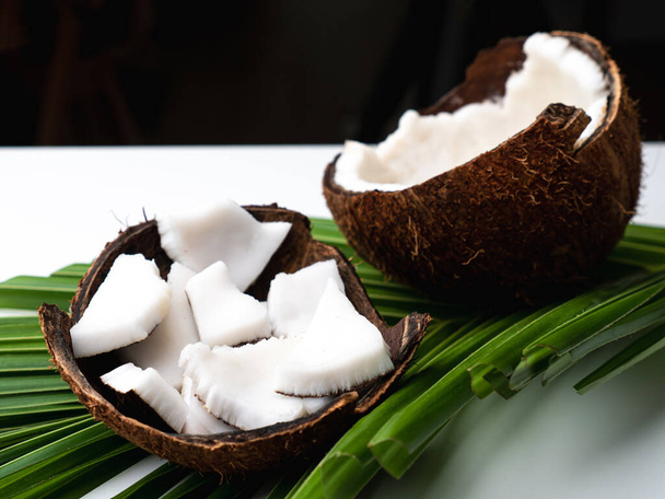 Kokosfleisch und Kokosblatt auf weißem Tisch. - Foto, Bild