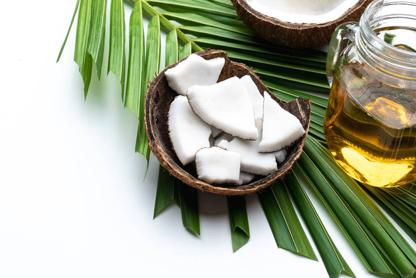 Coconut meat and coconut oil in glass bottle on coconut leaf. - Foto, imagen