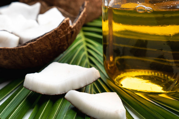 Kokosové maso a kokosový olej ve skleněné láhvi na kokosovém listu. - Fotografie, Obrázek