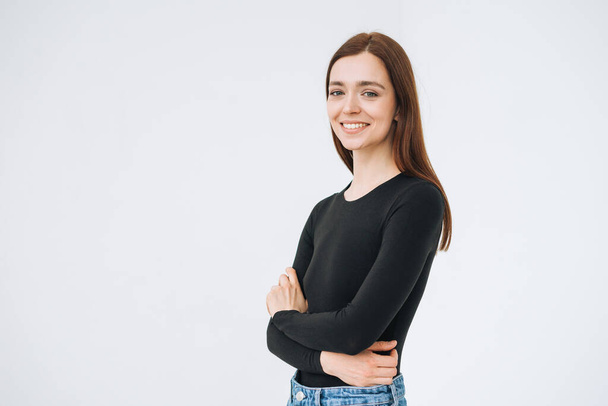 Portrait of happy young beautiful woman with dark long hair in black longsleeve and jeans on the white background isolated - 写真・画像