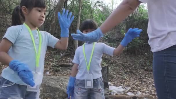 Een groep Aziatische vrijwilligersfamilies hebben hun handen bij elkaar gestoken voordat ze vuilnis opraapten bij de rivier. Gooi afval in de vuilnisbak om het milieu te helpen redden. Wereldmilieudag - Video