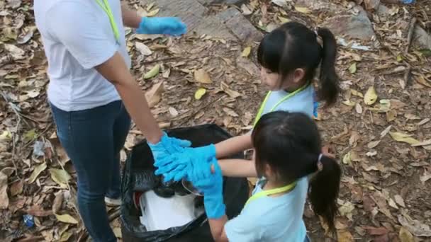 Een groep Aziatische vrijwilligersfamilies hebben hun handen bij elkaar gestoken voordat ze vuilnis opraapten bij de rivier. Gooi afval in de vuilnisbak om het milieu te helpen redden. Wereldmilieudag - Video