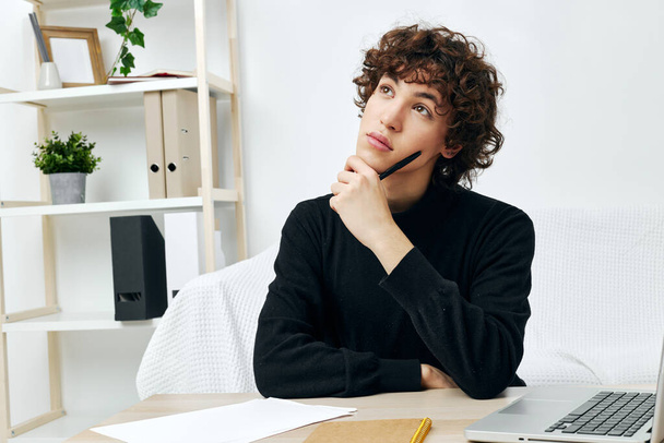 curly guy sitting on the couch at the table in front of a laptop communication - Photo, Image