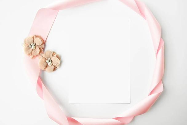 Blank greeting card mockup with pink flowers and pink ribbon frame. Top view, flatlay, white copy space. Simple and minimalistic concept. - Φωτογραφία, εικόνα