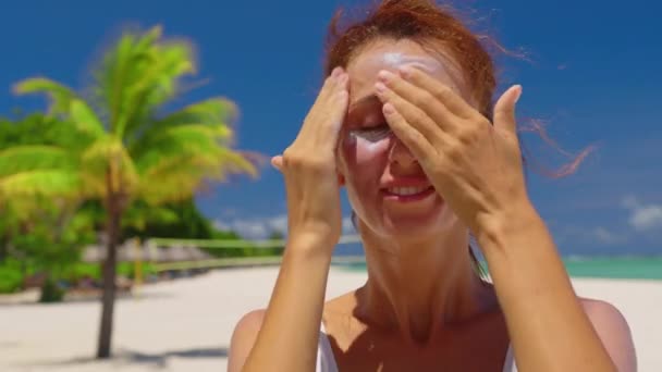 Una donna passa la crema solare sul viso in una giornata di sole - Filmati, video
