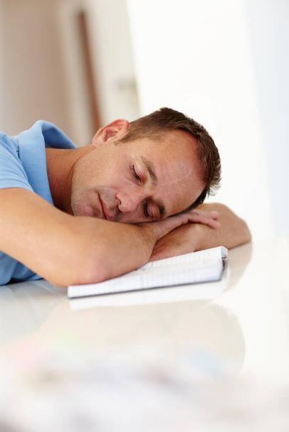 Kluczem do produktywności są drzemki. Dojrzały mężczyzna śpi wygodnie z głową na biurku. - Zdjęcie, obraz