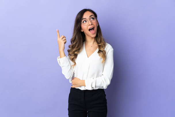 Young caucasian woman isolated on purple background intending to realizes the solution while lifting a finger up - Photo, Image