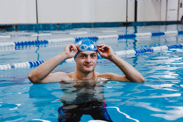 hispanic young man swimmer athlete wearing cap and goggles in a swimming training at the Pool in Mexico Latin America - Photo, Image