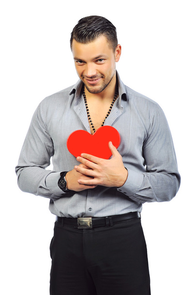Joven hombre guapo sosteniendo un juguete rojo en forma de corazón
 - Foto, Imagen