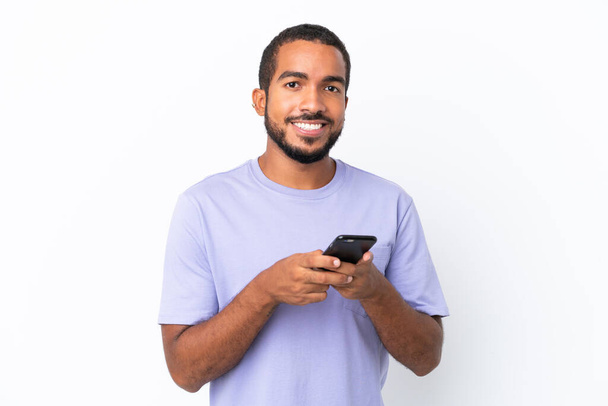 Nuori Ecuadorin mies eristyksissä valkoisella taustalla lähettää viestin matkapuhelimella - Valokuva, kuva