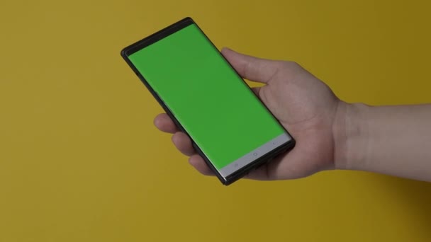 Pantalla de Smartphone. Teléfono inteligente aislado en el fondo de color. Técnica de croma de pantalla verde. Hombre mano tocando en la pantalla verde del teléfono móvil. Uso de la pantalla del teléfono inteligente. gestos de manos. Imágenes 4K. - Metraje, vídeo