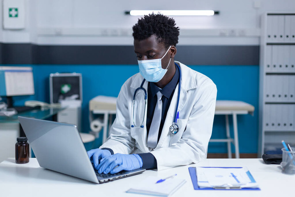 Klinikai orvos ül a számítógép, miközben elemzi a betegség jelentések és a kovid előfordulási arány - Fotó, kép
