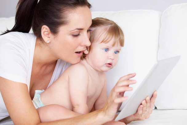 A jogar no tablet. Uma menina bonita e sua mãe olhando para um tablet digital juntos. - Foto, Imagem
