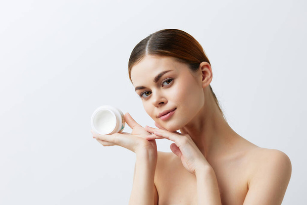 mooie vrouw pot van crème in handen schone huid poseren geïsoleerde achtergrond - Foto, afbeelding