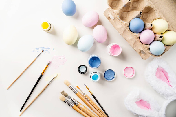 Paskalya için hazırlanan kadın. Tatil için ev dekorasyonu. Paskalya yumurtalarını pastel boyalarla boyamak, üst görünüm düzlük, tatil arka planı - Fotoğraf, Görsel