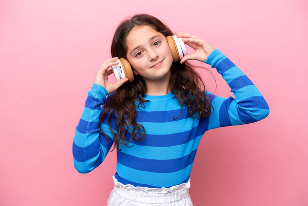 Kleines Mädchen isoliert auf rosa Hintergrund Musik hören - Foto, Bild