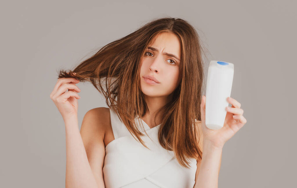 Young woman with bootle shampoo is very upset because of hair loss. Haircut and healthy haircare. Serious hair loss problem for health care shampoo. - Φωτογραφία, εικόνα