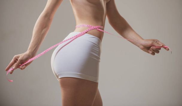 Uma jovem mulher a medir a cintura. Feminino ajuste corpo magro. - Foto, Imagem