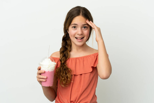 Маленька біла дівчинка з полуничним молочним коктейлем ізольована на білому тлі з несподіваним виразом
 - Фото, зображення