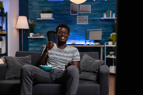 Усміхнений афроамериканський хлопець грає під час перегляду комедійного фільму
 - Фото, зображення