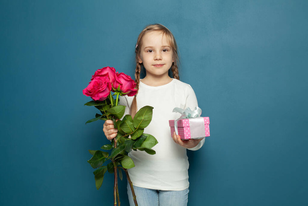 Niña pequeña niña con flores rosas y caja de regalo. 8 tarjeta de marzo o concepto de día de las madres - Foto, Imagen