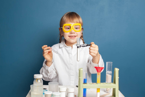 Счастливая маленькая девочка с фляжками для химии. Концепция науки и образования - Фото, изображение