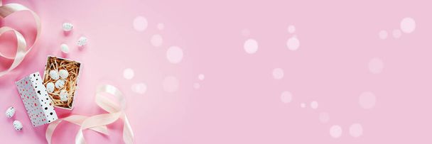Baner wielkanocny z pisankami w pudełku z różowymi wstążkami na różowym tle - Zdjęcie, obraz