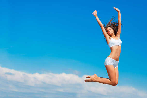 Щасливий, що я йду. Знімок щасливої молодої жінки, що стрибає високо в небі
. - Фото, зображення
