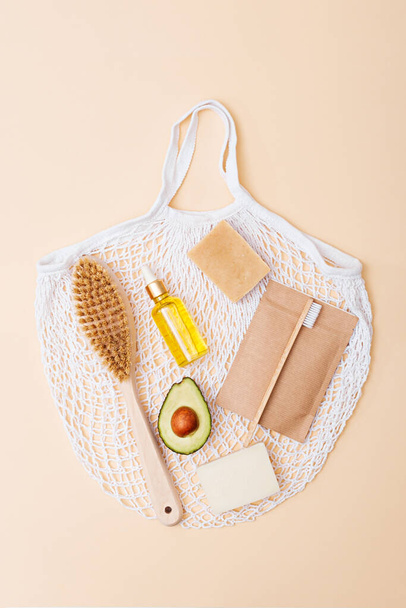 vertical dry massage brush, bamboo toothbrush, avocado body oil, natural soap on cotton bag on beige background, eco body skin care concept - Photo, Image