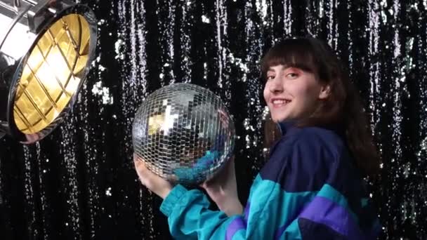 Young sporty woman 80 and 90s style. 90s fashion positive girl at disco party with disco ball in hands. - Footage, Video